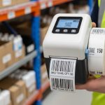 Worker using portable barcode label printer for warehouse labeling