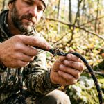 Hunter inspecting a frayed nylon rope for damage outdoors.