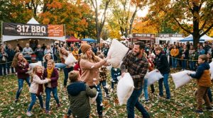 Families and friends enjoying a lively pillow fight outdoors at the 317 BBQ Broad Ripple event in Indianapolis on a fall afternoon
