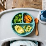 Colorful balanced meal with avocado and sweet potato on baby highchair.